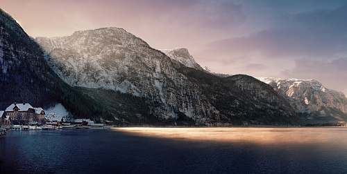 landscape brown and white house beside body of water covered with shadow of mountain mountain