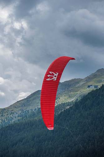 gliding person riding red parachute at daytime leisure activities