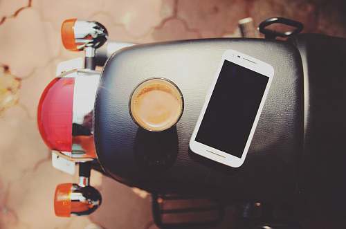 phone white smartphone on black leather motorcycle seat coffee