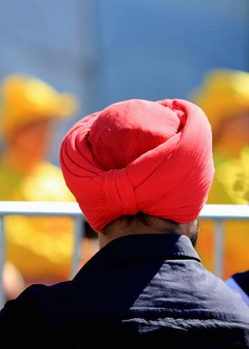 clothing man with red turban facing back near railings turban