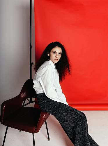 clothing sitting woman wearing white long-sleeved shirt near orange tarpaulin chair