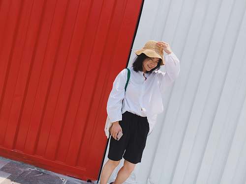 clothing smiling woman standing beside red and white wall human