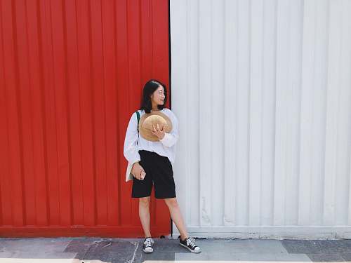 clothing women near a red and white wall during daytime footwear