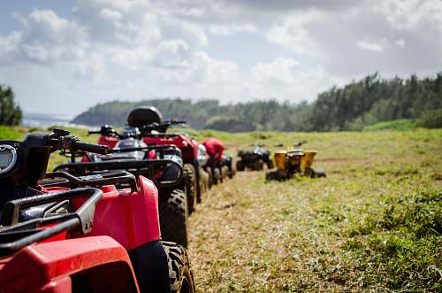 transportation focus photography of ATV's falling in line on grass field vehicle