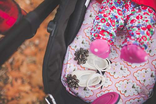 infant pair of white crib shoes on pink and black stroller feet