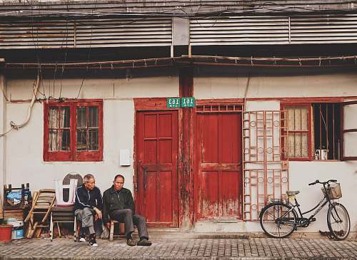 bike two men sits beside brown wooden door during daytime chair