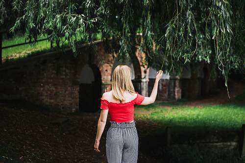 girl woman standing grabbing green tree leaf wearing red t-shirt woman