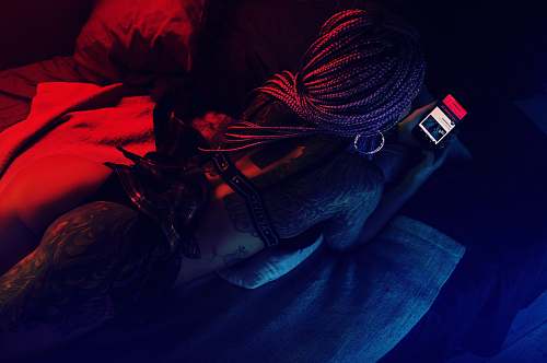 red woman lying on bed holding smartphone light