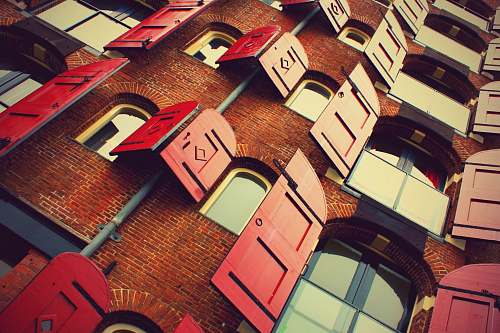 brick brown brick building with opened red wooden windows during daytime windows