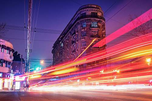 city time-lapse photography of cars passing through the road between buildings during night time urban