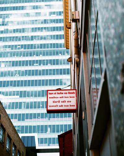 urban wihte and red sign board near mirror wall building message