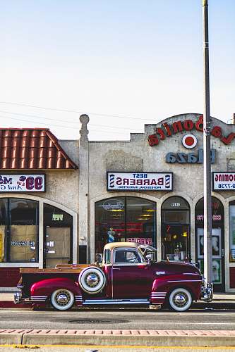 city classic red coupe parked beside barber store facade barbershop