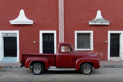 truck red single cab pickup truck parked outside brown builing vehicle