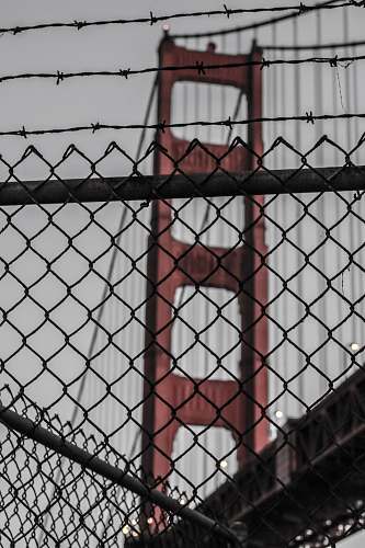 urban photo of diamond link fence near red bridge at daytime chainlink fence