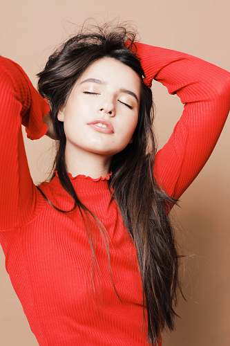 apparel woman in red turtleneck sweater holding her hair and closing eyes sleeve