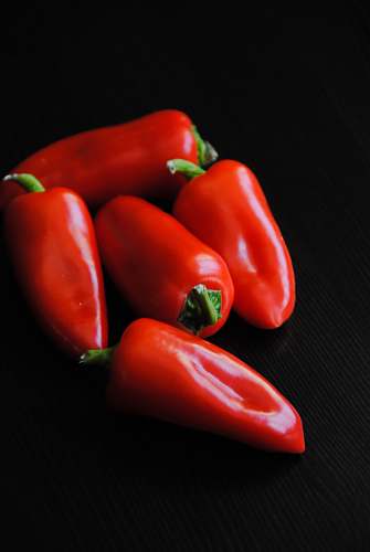 vegetable five red bell peppers on black textile plant