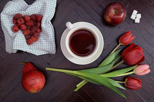 fruit teacup on saucer near apple and tulip flower drink