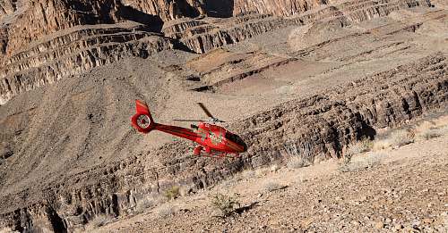 canyon red R/C helicopter flying over gray sand mountain