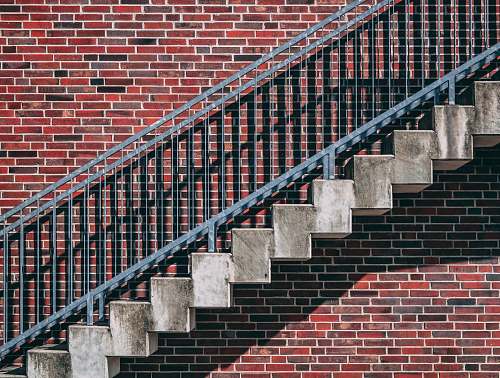grey gray metal stair beside red brick wall abstract