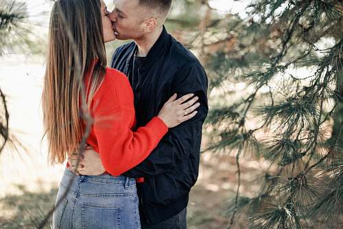 people couple kissing beside green leaf trees during daytime person
