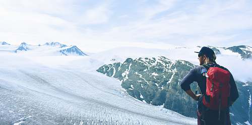 mountain man in red backpack standing on snowy land snow