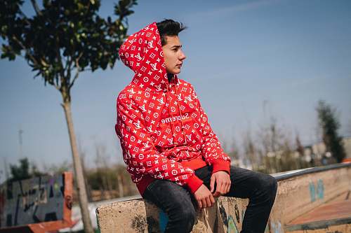 person man sitting on concrete bench wearing Supreme X Louis Vuitton Monogram Canvas hoodie people