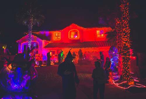 person people standing near house with red light decor during night time people