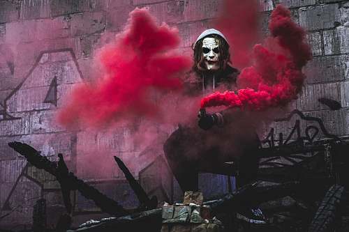 smoke person in Joker cosplay holding smoke grenade clown