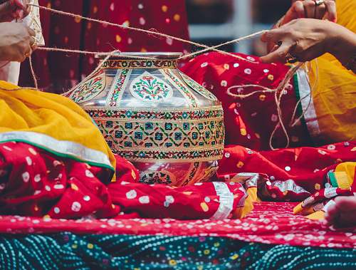 person photo of two person tying brown and green floral pot using rope people