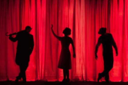 person silhouette of three performers on stage stage