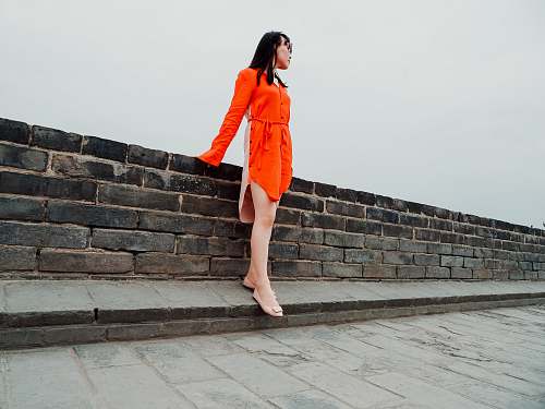 person woman standing beside brick wall people