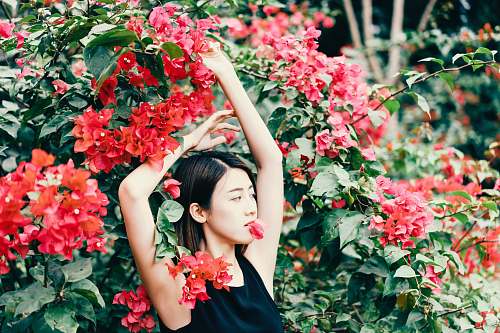 person woman standing in front of red flowers plant