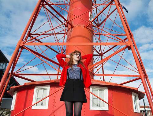 person woman standing under red metal tower people