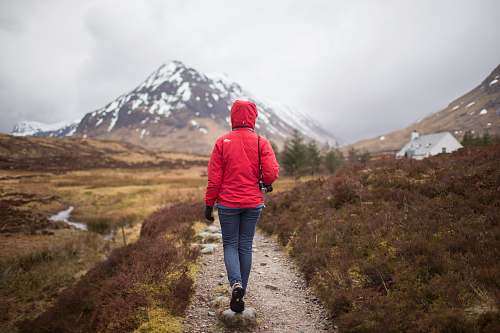 person woman walking on brown pathway near house people