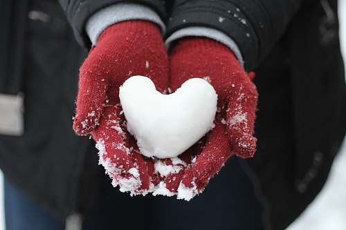 hand person holding heart-shaped snow holding
