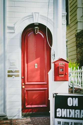 postbox closed red wooden door beside No Parking signage red