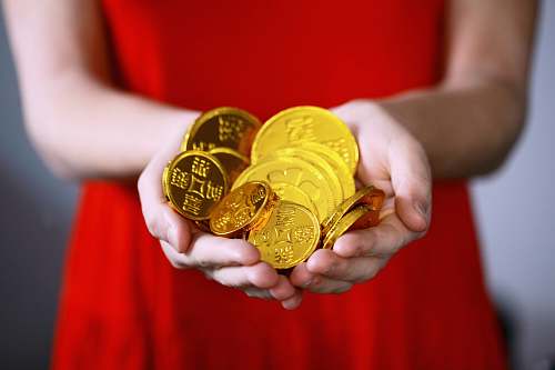 gold person holding gold-colored ching coins coin