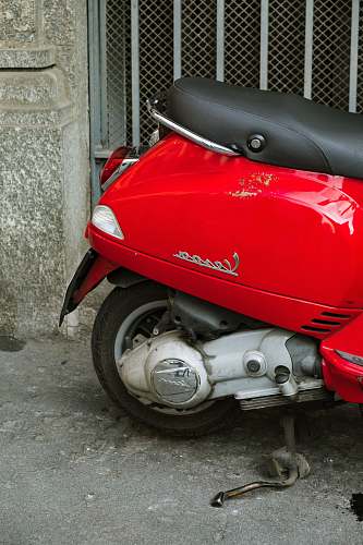 vespa red Vespa motor scooter parked near gate motor scooter