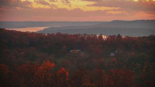 outdoors aerial photography of house surrounded by trees beside shore during daytime dawn