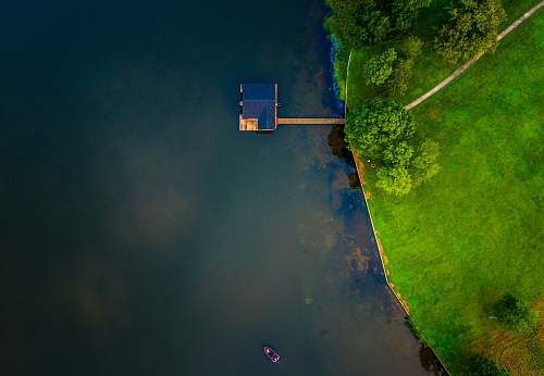 trees bird's eye view of blue wooden house on body of water near trees aerial