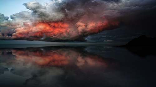 sky body of water under red and white clouds cloud