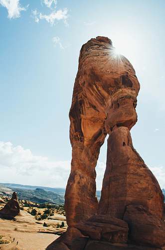 human brown boulder near canyon under blue sky person
