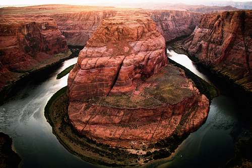 canyon brown rocky mountain and body of water at daytime horseshoe bend