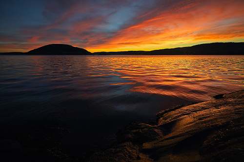 outdoors calm sea with silhouette mountain during sunset sunset