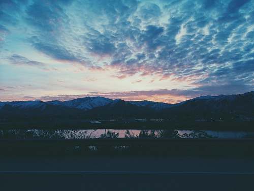 dawn mountain near body of water under white and blue sky during nighttime photography dusk
