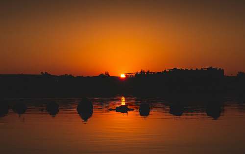 outdoors silhouette of body of water under orange sky dawn