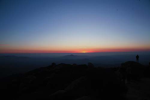 sky silhouette of person standing on cliff sunset