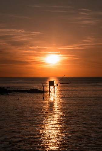 flare silhouette photography of a platform in the sea during golden hour light