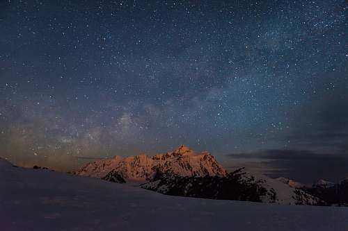 sky mountain covered with snow during nighttime view stars