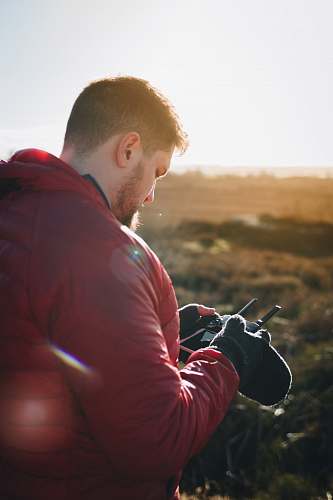 human man in red puffer jacket holding remote control person